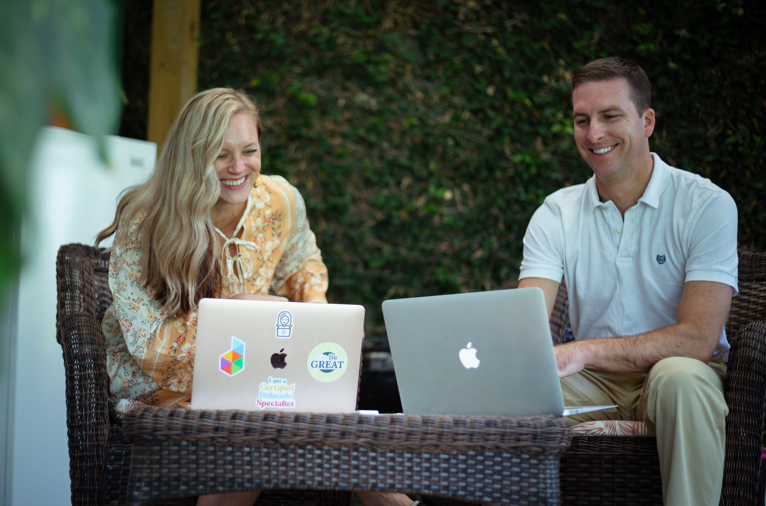Two people collaborating on laptops outdoors